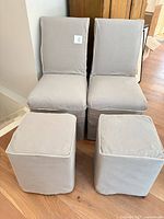 Two grey slipcovered dining chairs and two matching cube stools