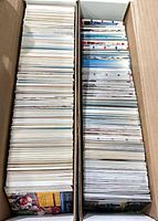 Two long cardboard boxes filled with stacked loose trading cards