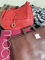 Group shot showing red shoulder bag, leopard tote portion, black & white quilted tote, and brown briefcase