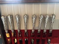 Row of ornate sterling knife handles in chest
