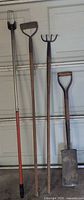 Four garden tools leaning against garage door