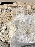 Group of crocheted table linens including tablecloth, vanity scarf, and assorted doilies