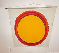 Full view of textile wall hanging showing sun design and top hanging rod