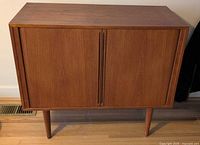 Front view of cabinet closed showing teak-style veneer and tapered legs
