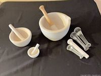 Three porcelain mortar and pestle sets with four extra pestles displayed on black background