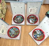All four Poole Pottery plates in boxes opened to show artwork