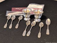 Lot overview showing two toothpick holders, six spoons and two polishing cloth packets