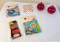 Overview of three packaged tea towels, strawberry dishcloth, two pink onion holders