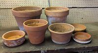 Group shot of five terracotta pots and four saucer plates on workbench