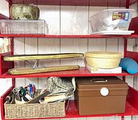 Overview of shelving with ceramic bowl, plastic organizers, pressing ham, wicker baskets, brown sewing box and fabric tote
