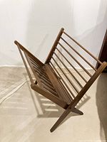 Side perspective of wooden folding magazine rack showing slatted sides and X-frame legs