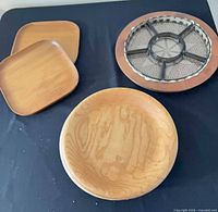 Overall lot showing two square plates, round platter with glass insert, and round wooden lazy susan