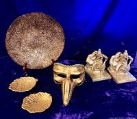 Group shot showing brass bookends, gold platter, two leaf dishes, and Venetian mask