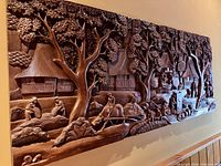 Full view of the carved wall panel showing entire village scene and length