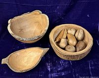 Three wooden bowls and carved fruit pieces displayed
