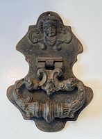 Front view showing cherub motif, handle, rusted finish