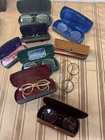 All eight spectacles displayed with open cases on cloth surface