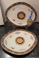 Two Bacchus Limoges porcelain pierced oval servers on stands showing front design and labels