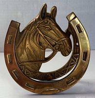 Front view of brass horseshoe door knocker showing horse head and full design