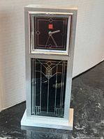 Front view showing brushed silver-tone case, black dial, geometric glass panel