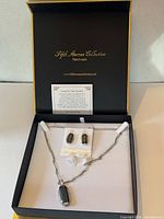 Open presentation box showing necklace, earrings, branding