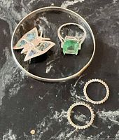 Full lot showing bangle with butterfly, green cocktail ring, and two pavé bands