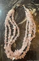 Four-strand rose quartz chip necklace laid flat showing strands and clasp