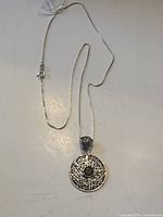 Pendant necklace laid out showing chain, clasp and pendant front