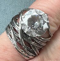 Close-up of ring on finger showing textured band and centre stone