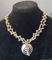 Full necklace on display bust showing two strands of pearls and shell pendant