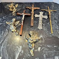 All seven items laid out: four crucifixes/crosses and three cherubs
