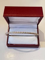 Bangle in open jewellery box showing stone-set front