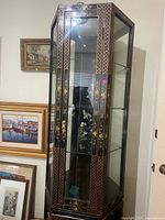 Full view of tall black lacquer display cabinet with glass panels and shelves