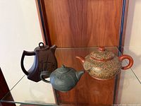 All three teapots on glass shelf
