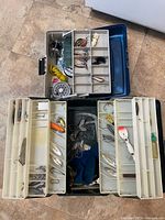Two open tackle boxes showing contents including reels and lures