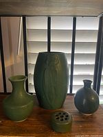 Group shot of four matte green pottery pieces