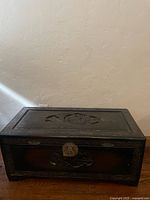 Full view of carved wooden trunk closed, showing lid design and front panel