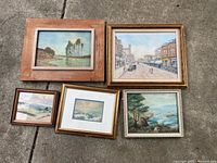 All five framed paintings laid out on concrete