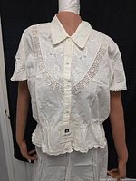 Front view of blouse and skirt on mannequin showing embroidery, lace trim and brand tag