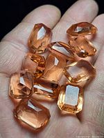 11 loose rectangular Padparadscha sapphires in hand