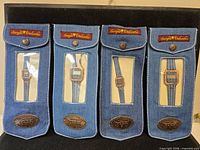 Front view of four denim pouches each displaying a watch