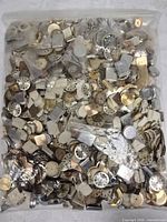 Full view of sealed plastic bag filled with assorted watch dials, cases and parts