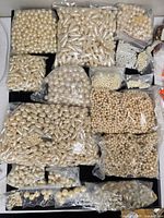 Overview of all bags of plastic imitation pearl beads on black background