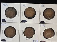 Six Canadian cents in cardboard holders labelled 1906, 1910, 1911, 1913, 1914, 1915