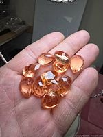 Hand holding eleven yellow pear-cut citrine stones