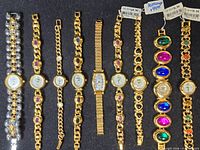 Overhead view of ten gold-tone and two-tone ladies bracelet watches on black foam