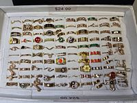 Full tray of 100 gold-tone costume rings displayed in slots