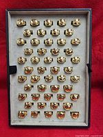 Tray containing rows of gold-plated Om signet rings