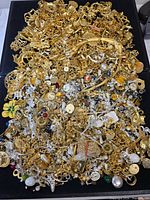 Wide view of entire mixed jewelry pile on black surface