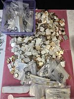overview of plastic bin and large pile of vintage watch dials with bagged crystals and gaskets
